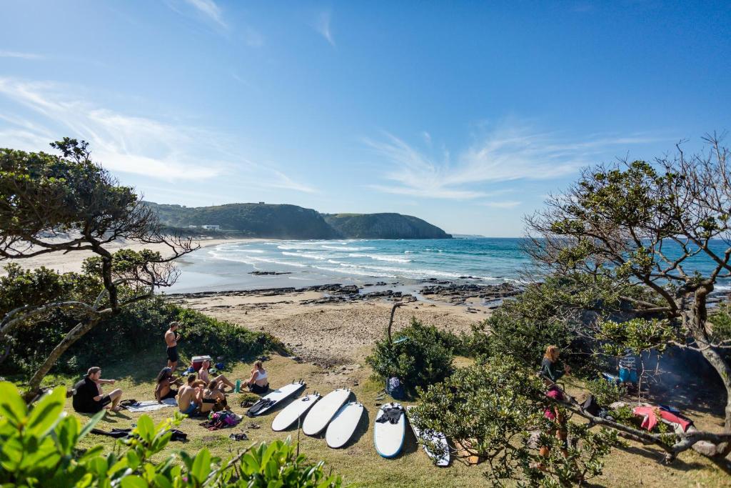 a group of people sitting on a beach with surfboards at Coffee Shack Adventure Backpackers & Self-Catering in Coffee Bay