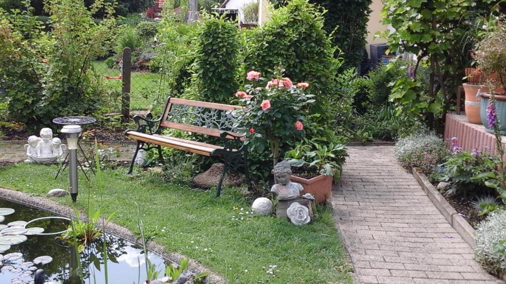 a garden with a bench and flowers and a pond at Drei Linden in Osterode in Osterode