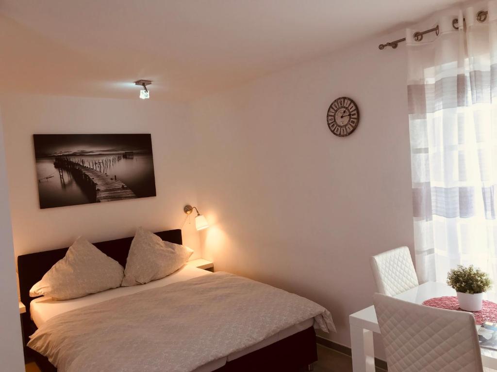 um quarto com uma cama e uma mesa com um relógio na parede em SWEET HOME OUTLETCITY em Metzingen