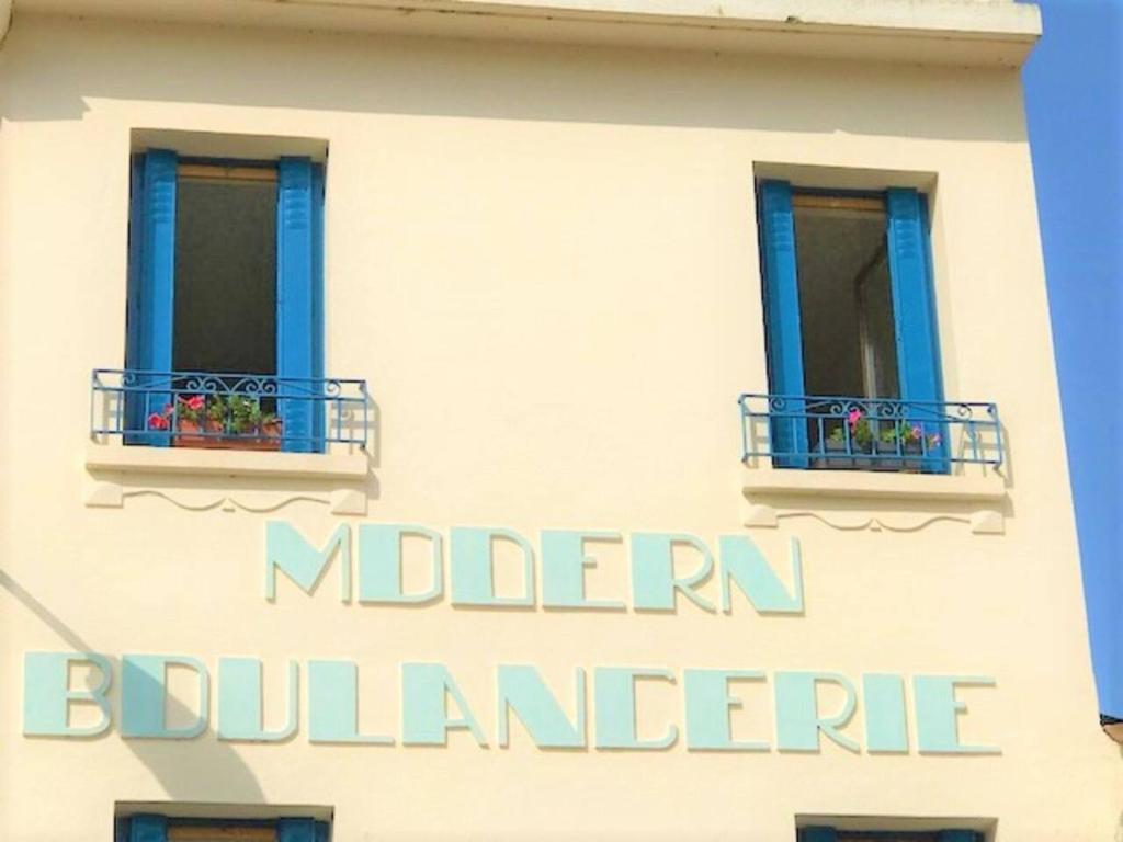 un edificio con dos ventanas con flores. en Modern Boulangerie, large 6 bedroom village house en Quillan