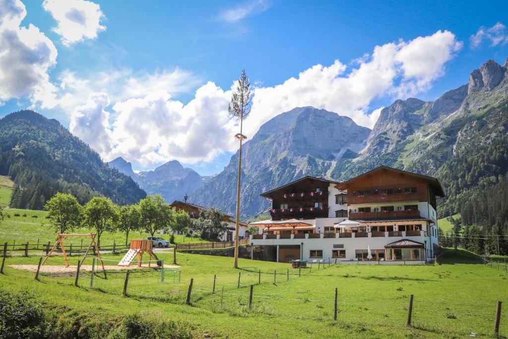 a building in a field with a playground in front of mountains at Berghotel Lämmerhof in Sankt Martin am Tennengebirge