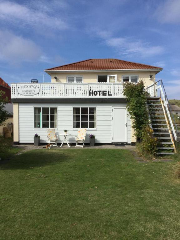 une maison blanche avec une terrasse couverte et un hôtel dans l'établissement Hotel Vestkysten, à Løkken