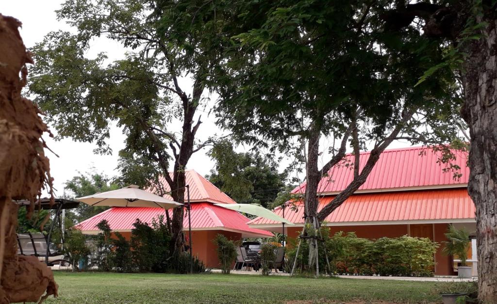 een gebouw met een rood dak met bomen en parasols bij Wapipathum Earthen House in Ban Na Lao