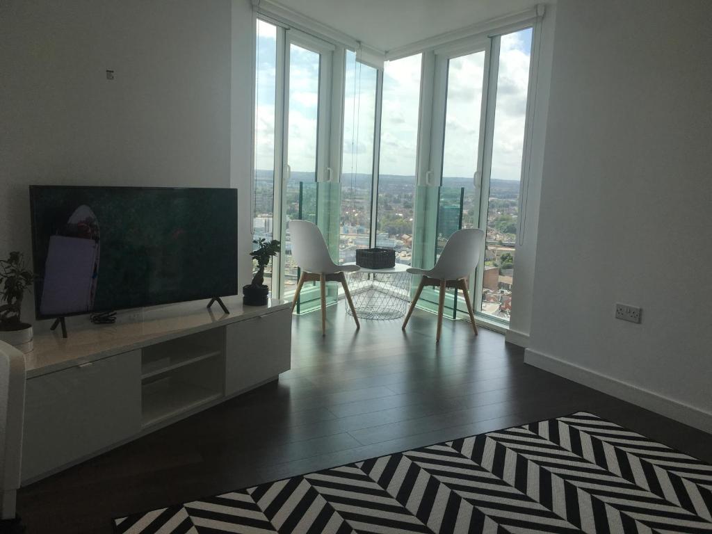 a living room with a flat screen tv and white chairs at GRAND SERVICED APARTMENTS***** in Croydon