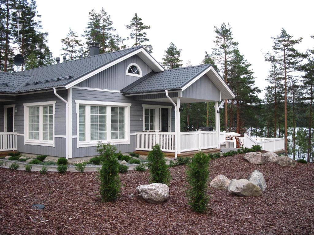 una casa con porche y patio con rocas en Kohtalo Travel Villa - Rautalampi, en Hankamäki