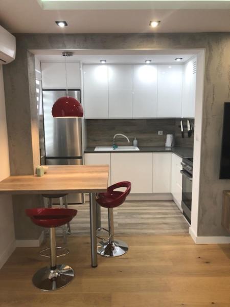 a kitchen with a wooden table and two red chairs at Apartament Dworcowa 30A 14 in Pasłęk