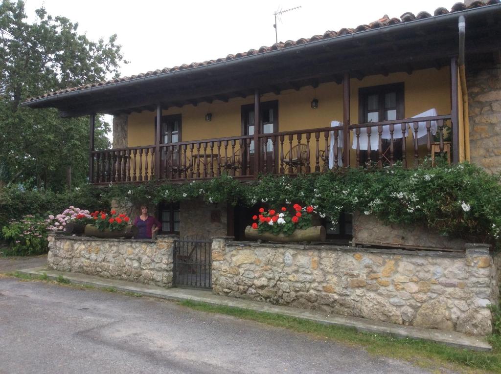 une femme assise devant un bâtiment avec balcon dans l'établissement Xuegu la bola, à Ceceda de Abajo