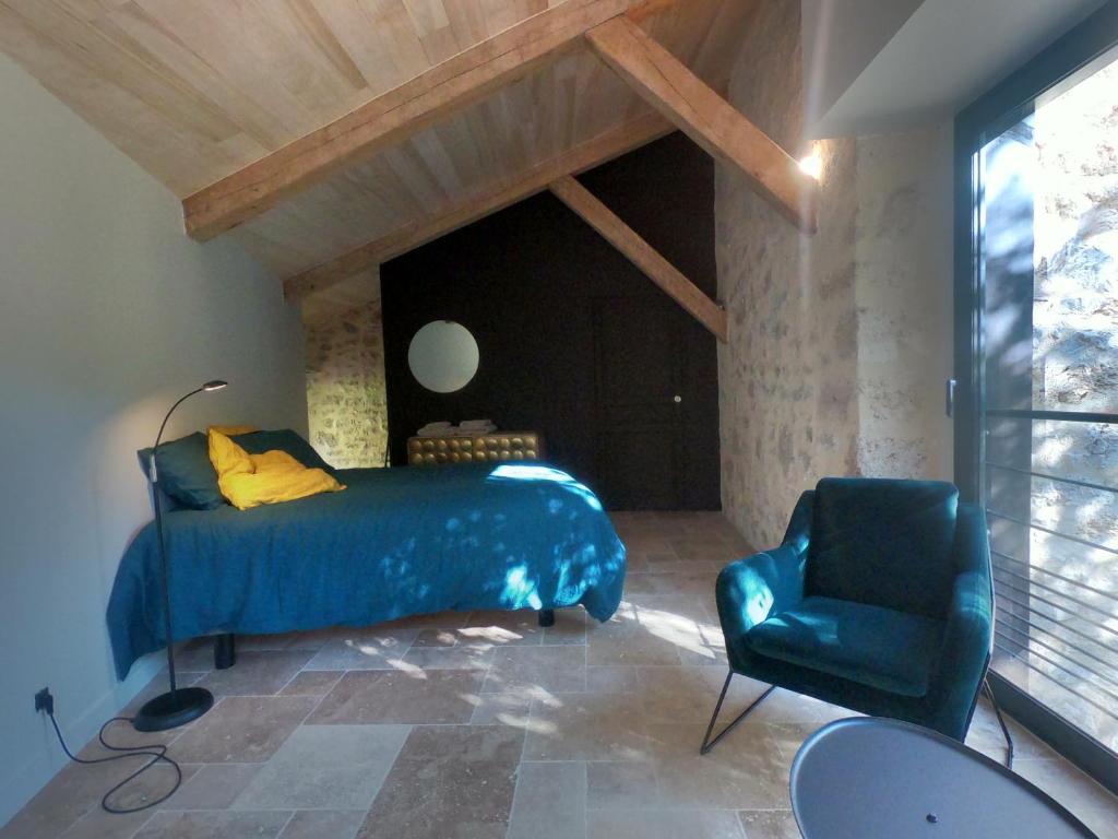 a bedroom with a blue bed and a chair at Les Jardins Sauvages in Cabrerets