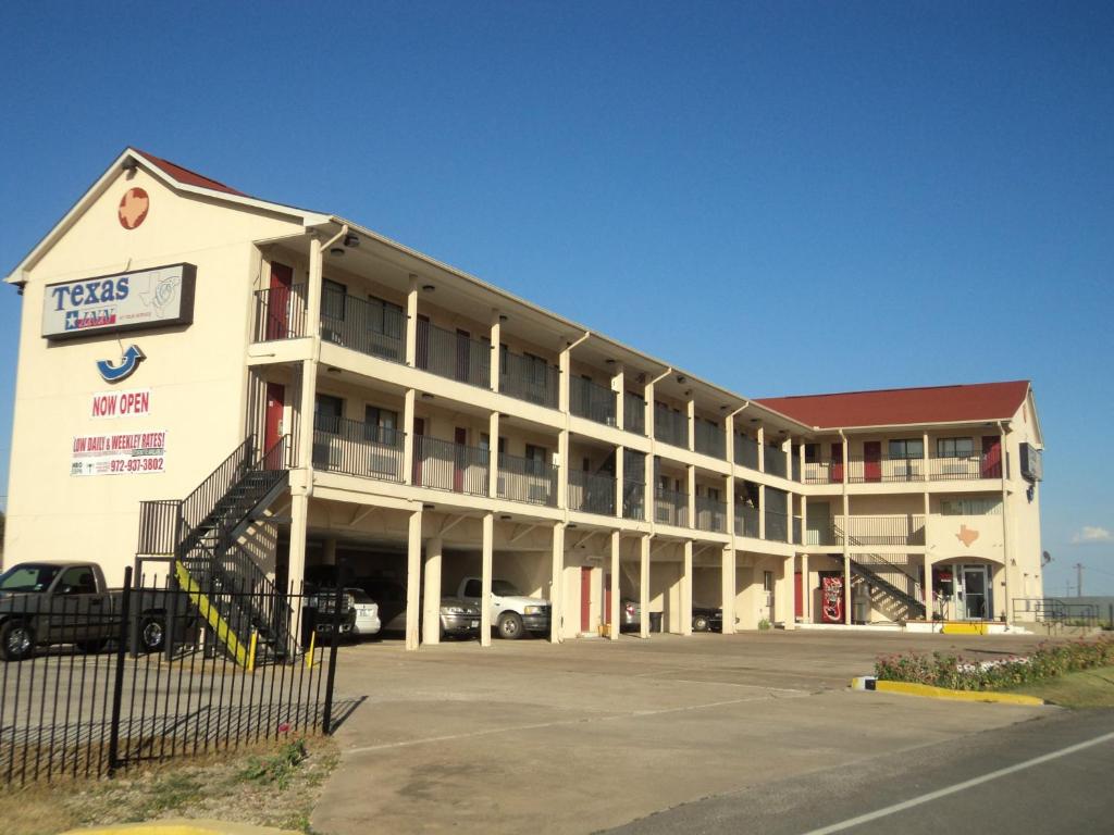 a large white building with a parking lot at Texas Inn Waxahachie in Waxahachie