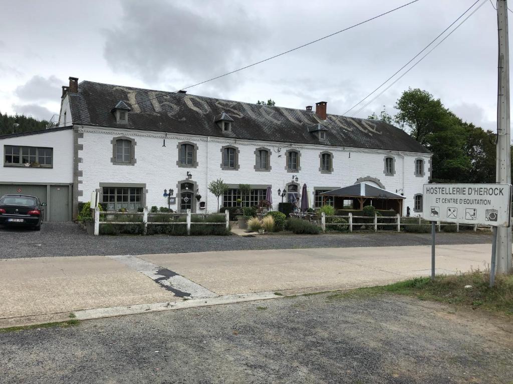 - un grand bâtiment blanc avec un panneau devant dans l'établissement Hostellerie Hérock, à Herock