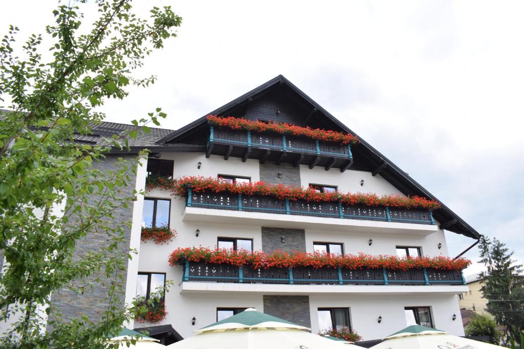 a white building with red flowers on the balconies at Vila Seva in Vatra Dornei