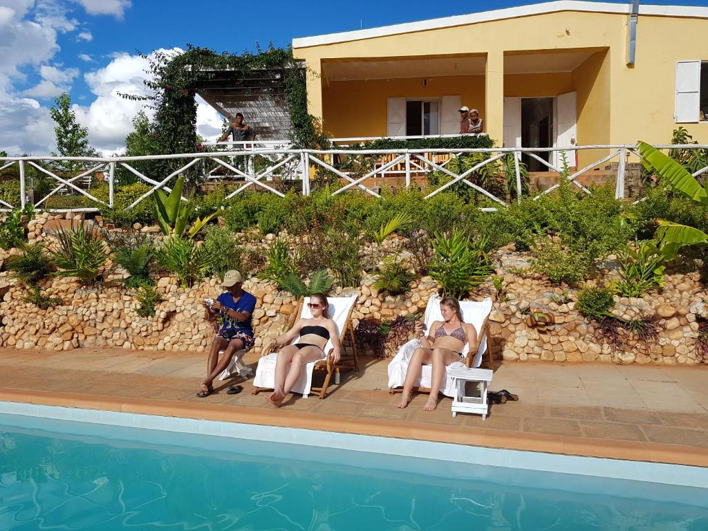 um grupo de pessoas sentadas em cadeiras ao lado de uma piscina em Ecole Lodge Antananarivo em Mahitsy