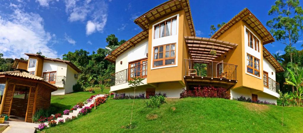 una casa grande en una colina con césped en Eco Pousada Quaresmeiras en Domingos Martins