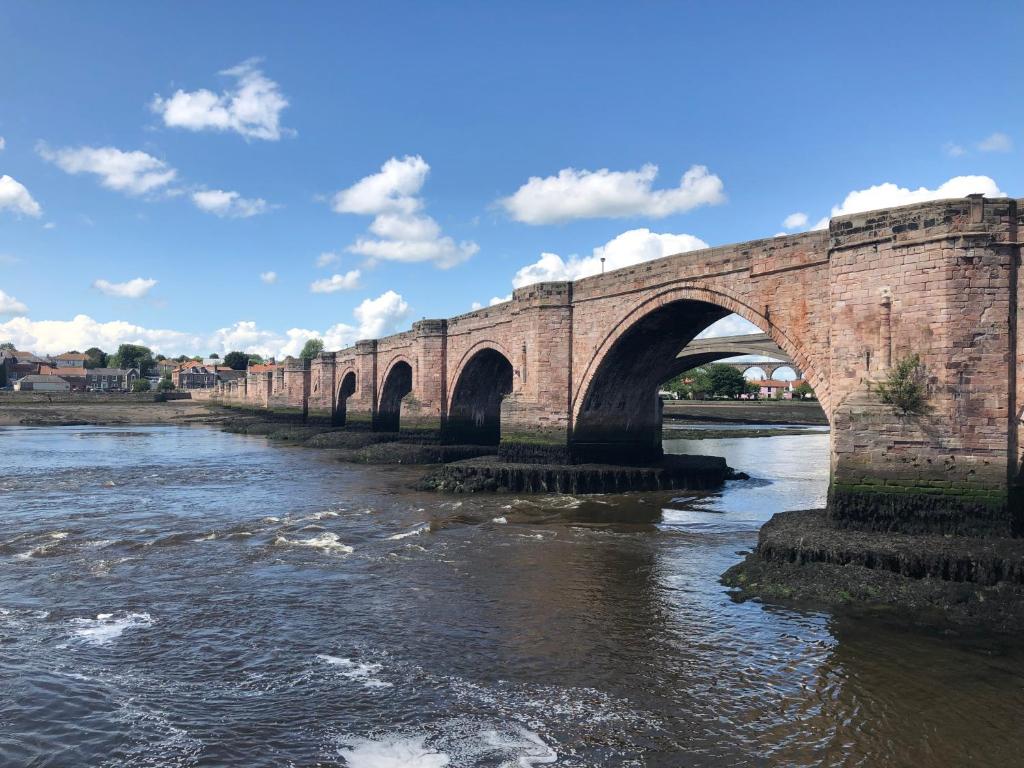 an old brick bridge over a river with water at Belmont House Boutique - the Kingsley collection in Berwick-Upon-Tweed