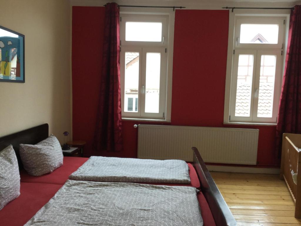 ゴスラーにあるBäckerstraßeの赤い壁のベッドルーム1室、窓2つ、ベッド1台が備わります。