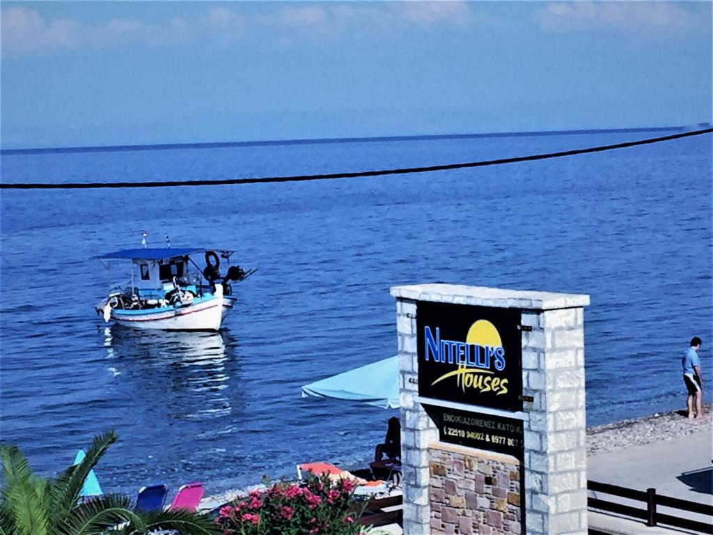 a boat in the water with a sign on the beach at Nitelli's Houses in Skála Néon Kydonión