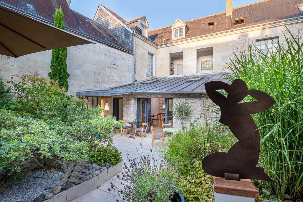 un jardin avec une statue en face d'un bâtiment dans l'établissement Hôtel de Biencourt, à Azay-le-Rideau