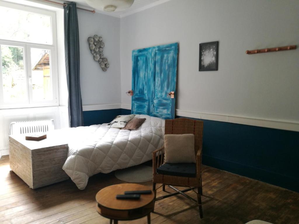 a bedroom with a bed and a chair and a window at Charmant Studio au calme à 5 min du centre ville in Saint-Claude
