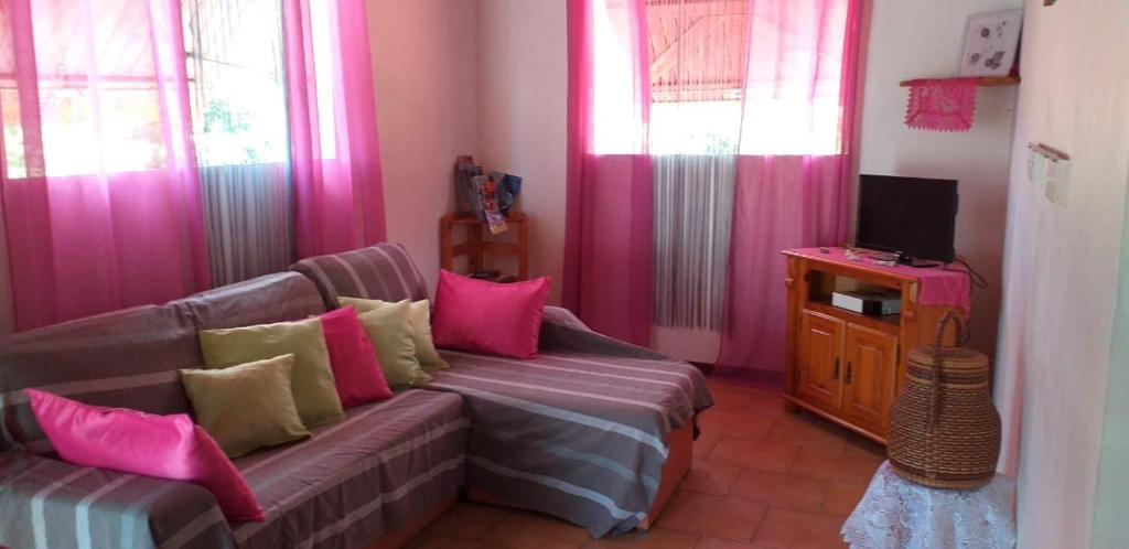 a living room with a couch and pink curtains at Kaloan in Capesterre-Belle-Eau