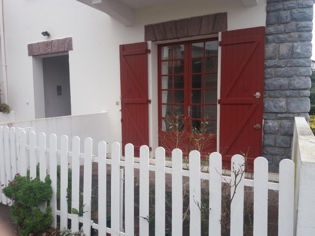 a white fence in front of a house with red doors at vacances in Urrugne