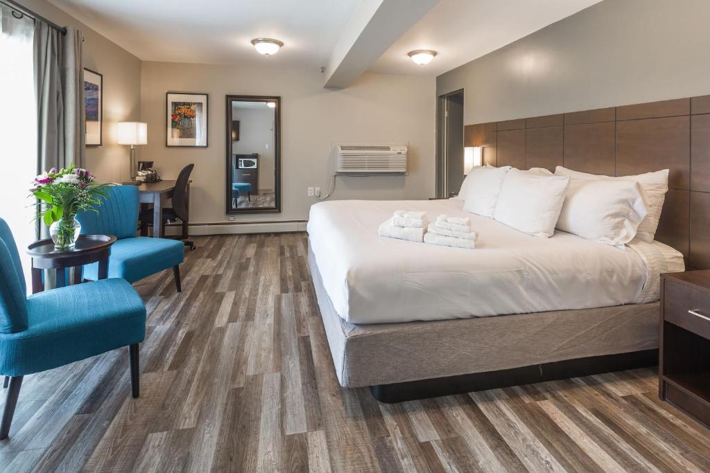 a bedroom with a large bed and a blue chair at Kent Inn in Lindsay