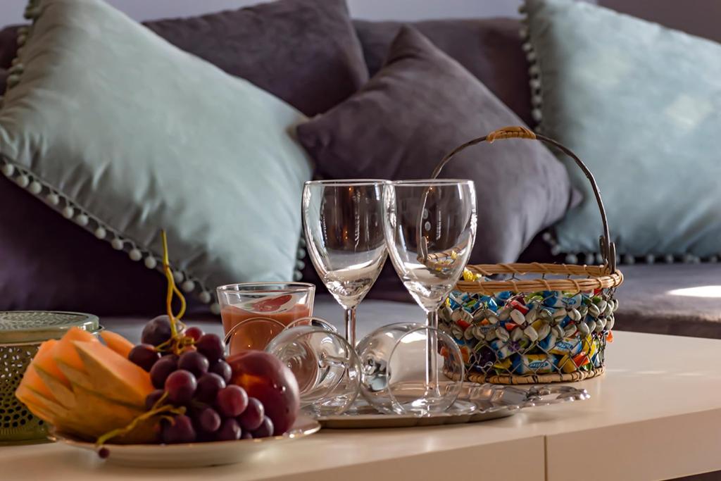 リエカにあるApartman Anabelaのワイングラス2杯とフルーツバスケット付きのテーブル