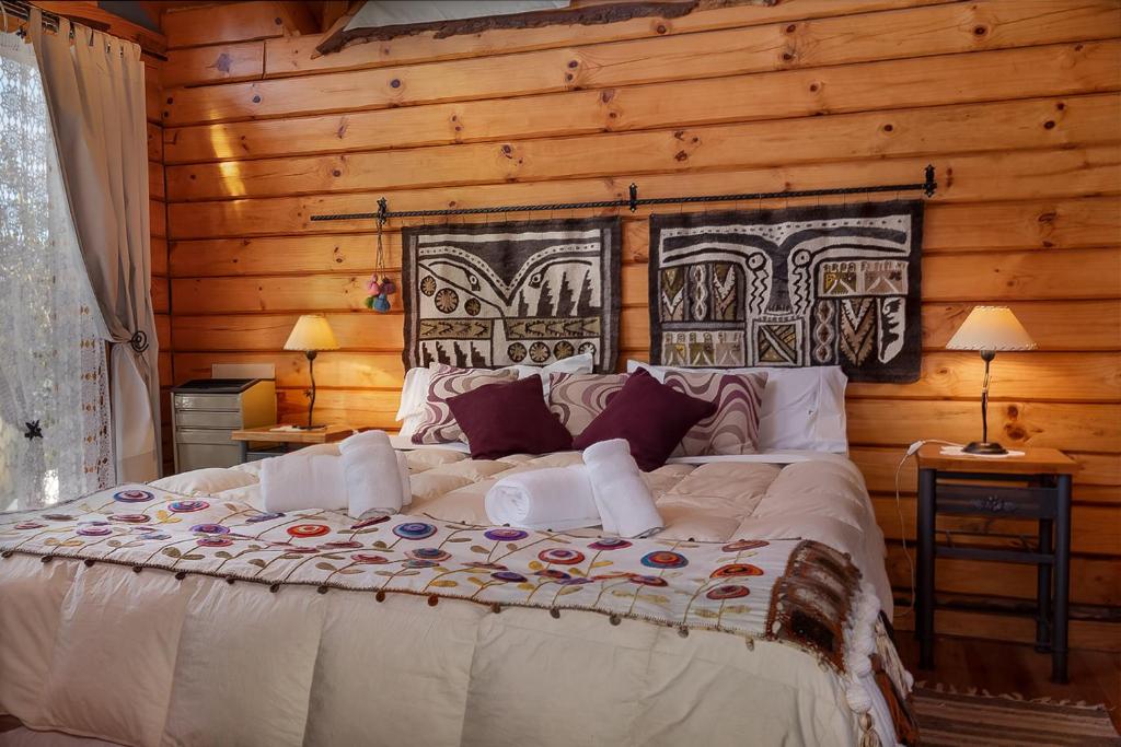 a bedroom with a large bed in a log cabin at Cabañas Bahiamia in Villa Pehuenia