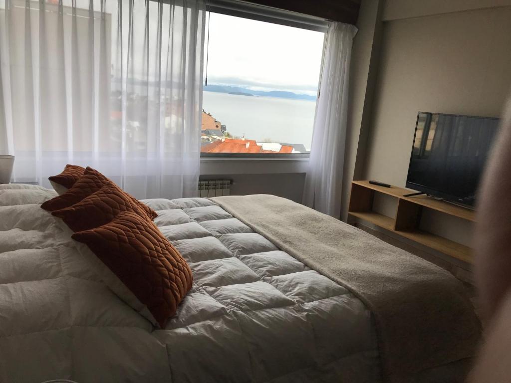 Bariloche View Apartment في سان كارلوس دي باريلوتشي: غرفة نوم بسرير كبير مع نافذة كبيرة
