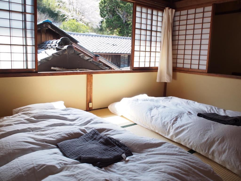Dos camas en una habitación con ventana. en NORA, en Numazu