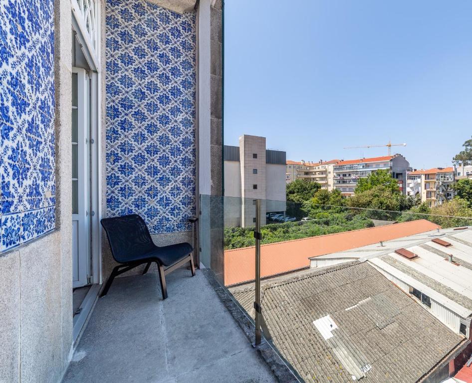 a chair sitting on the balcony of a building at Gallery Hostel in Porto