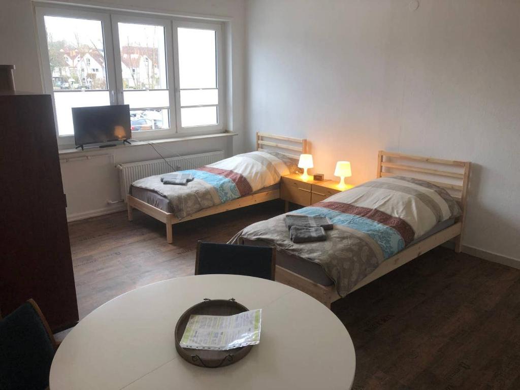 a small room with two beds and a table at Mühlweg-Appartment in Alzenau in Unterfranken
