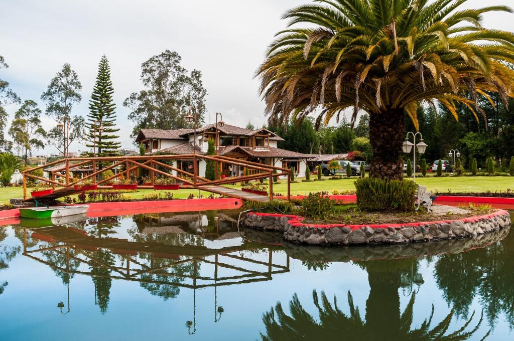 a house on a bridge over a pond with a palm tree at Casa d'Campo Tababela Hotel Boutique in Tababela