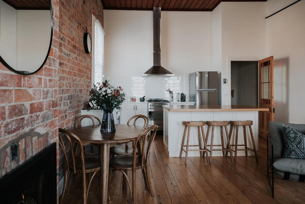 a kitchen with a table and chairs and a brick wall at Apartments on Belmore -The Ferguson in Yarrawonga