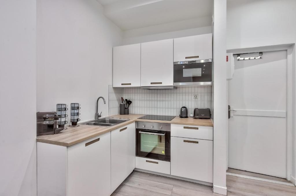 a white kitchen with white cabinets and a refrigerator at 35 - Urban Montmartre in Paris