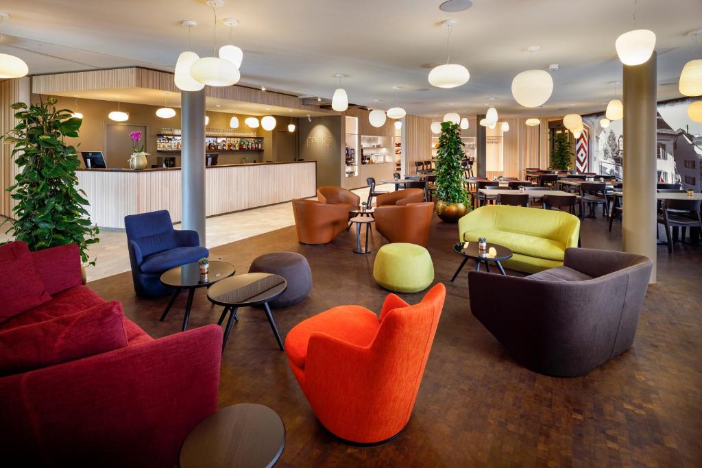 a lobby with colorful chairs and tables in a restaurant at Focus Hotel in Sursee