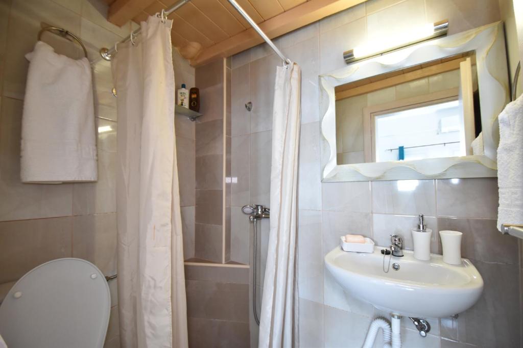 a bathroom with a sink and a toilet and a mirror at House With View in Paránimfoi