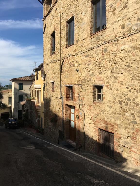 un antiguo edificio de piedra al lado de una calle en Loft De' Riccardi, en Chianni