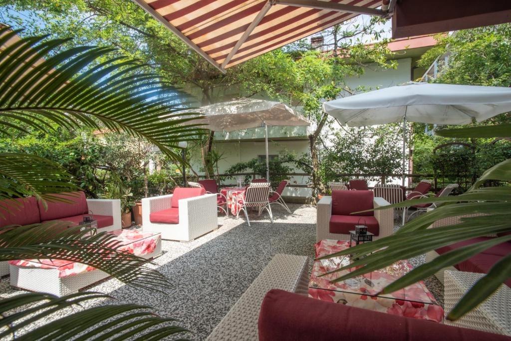 patio con sedie, tavoli e ombrellone di Hotel Adriaco a Grado