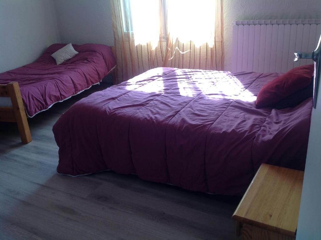 two beds in a bedroom with purple sheets and a table at Attrap'Rêves in Aspres-sur-Buëch