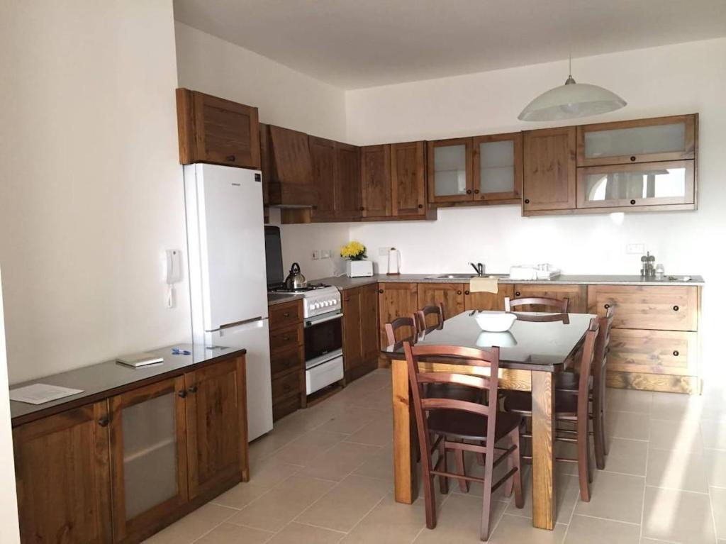 una cocina con armarios de madera y una mesa con sillas. en New and airy apartment in Marsalforn, en Żebbuġ