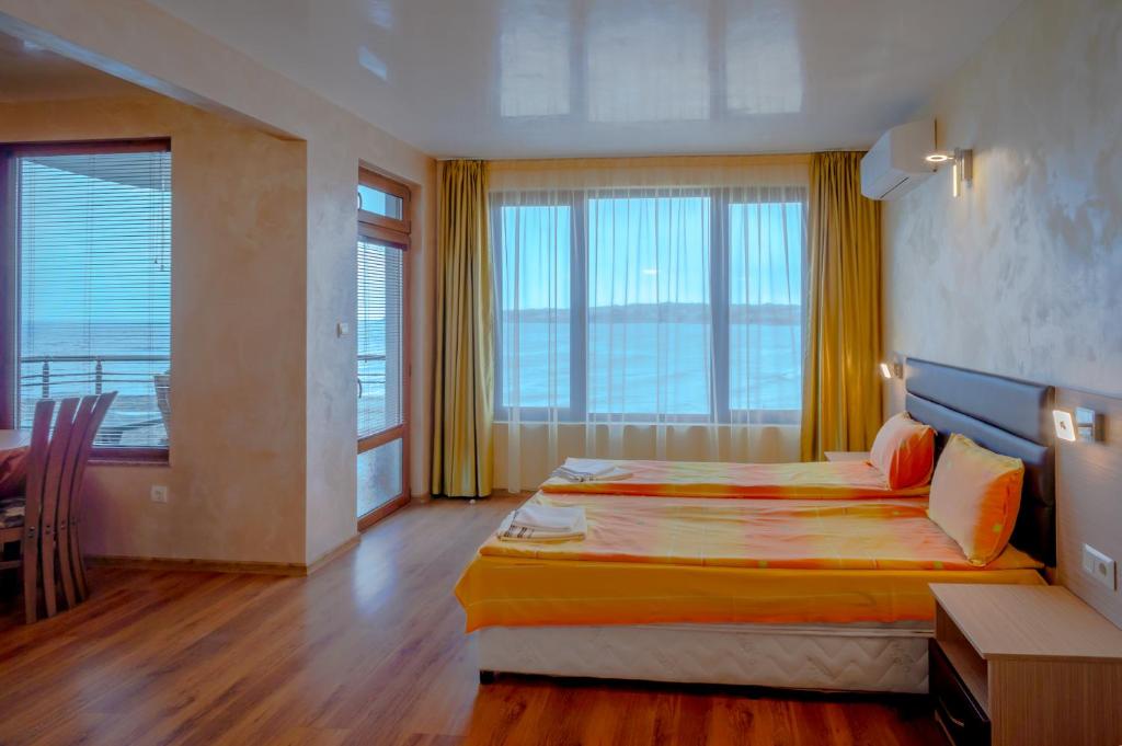 ソゾポルにあるGuest House Karamihaleviのベッド、テーブル、窓が備わる広い客室です。