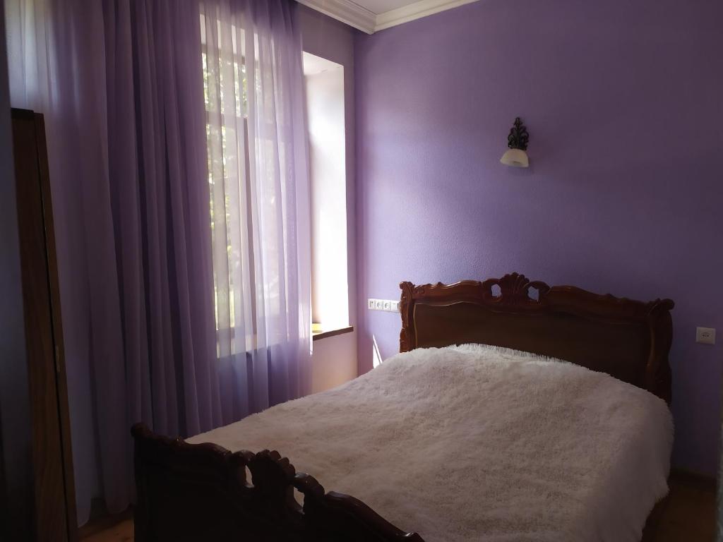a bedroom with a bed with purple walls and a window at Verishen Guest House B&B in Goris