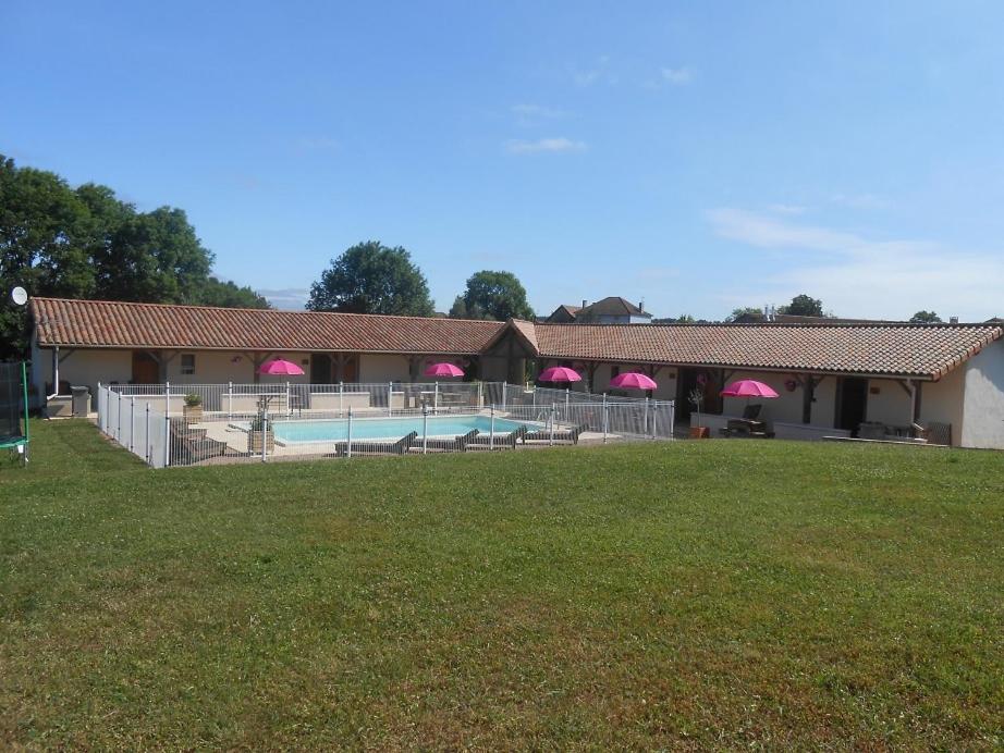 a building with a swimming pool with pink umbrellas at L'Auberge in Abjat