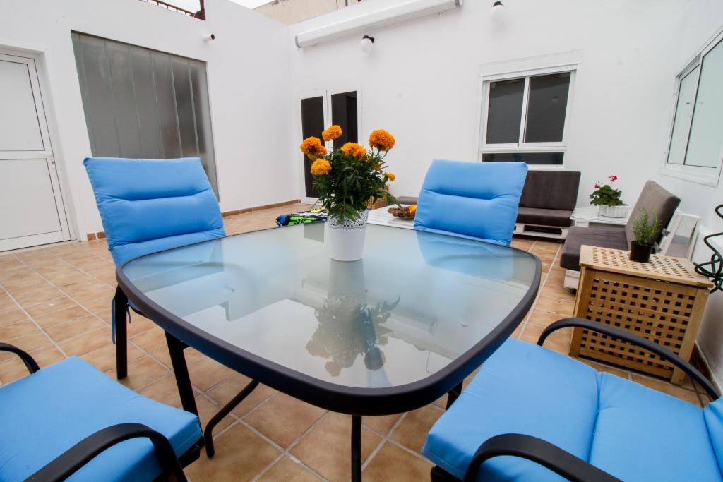 ラスパルマス・デ・グランカナリアにあるÁtico terraza Las Canterasのガラステーブル(青い椅子付)と花瓶