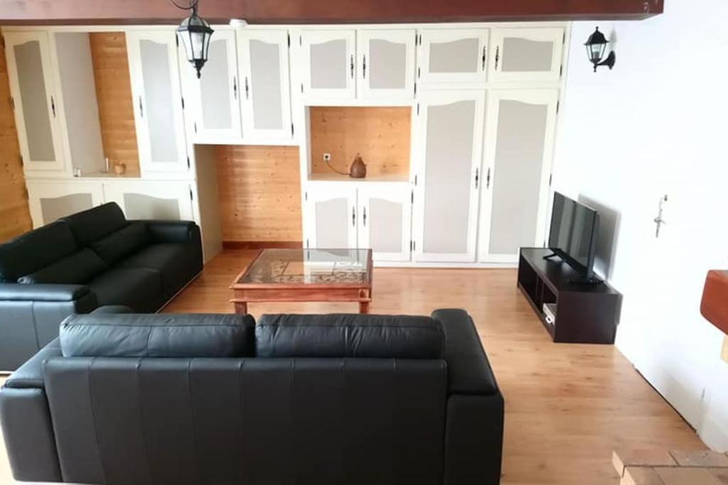 a living room with a black couch and a tv at Gîte Valentin in Dompierre-sur-Besbre