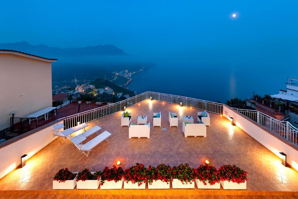 a balcony with white tables and chairs on a building at Gala Residence Villa Giovanna in Ravello