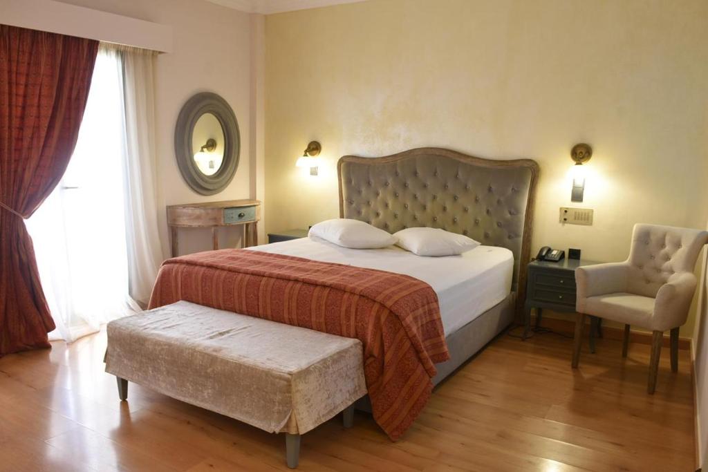 a hotel room with a bed, chair, and nightstand at Villa Orion Hotel in Athens