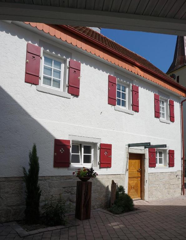 a white building with red shutters on it at Ferienhaus am Schönbuchrand in Herrenberg