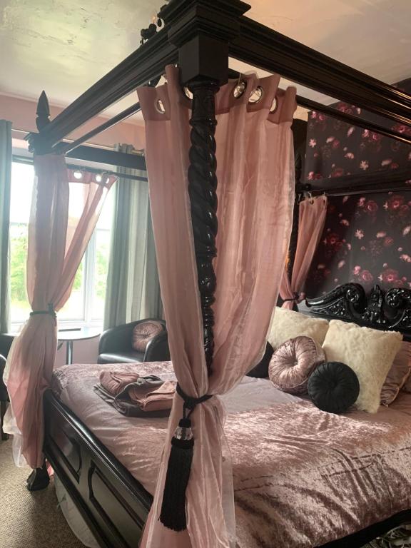 a bedroom with a canopy bed with pink curtains at Peniarth arms in Llanegryn