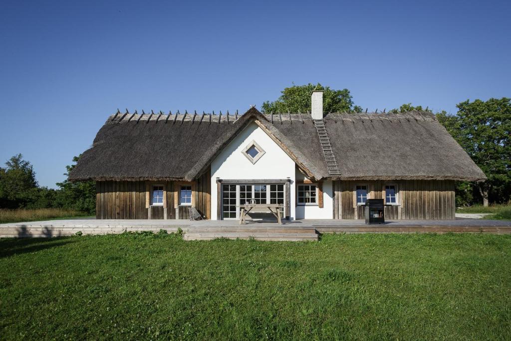 a house with a thatched roof on a field at Villa Bumba in Liigalaskma